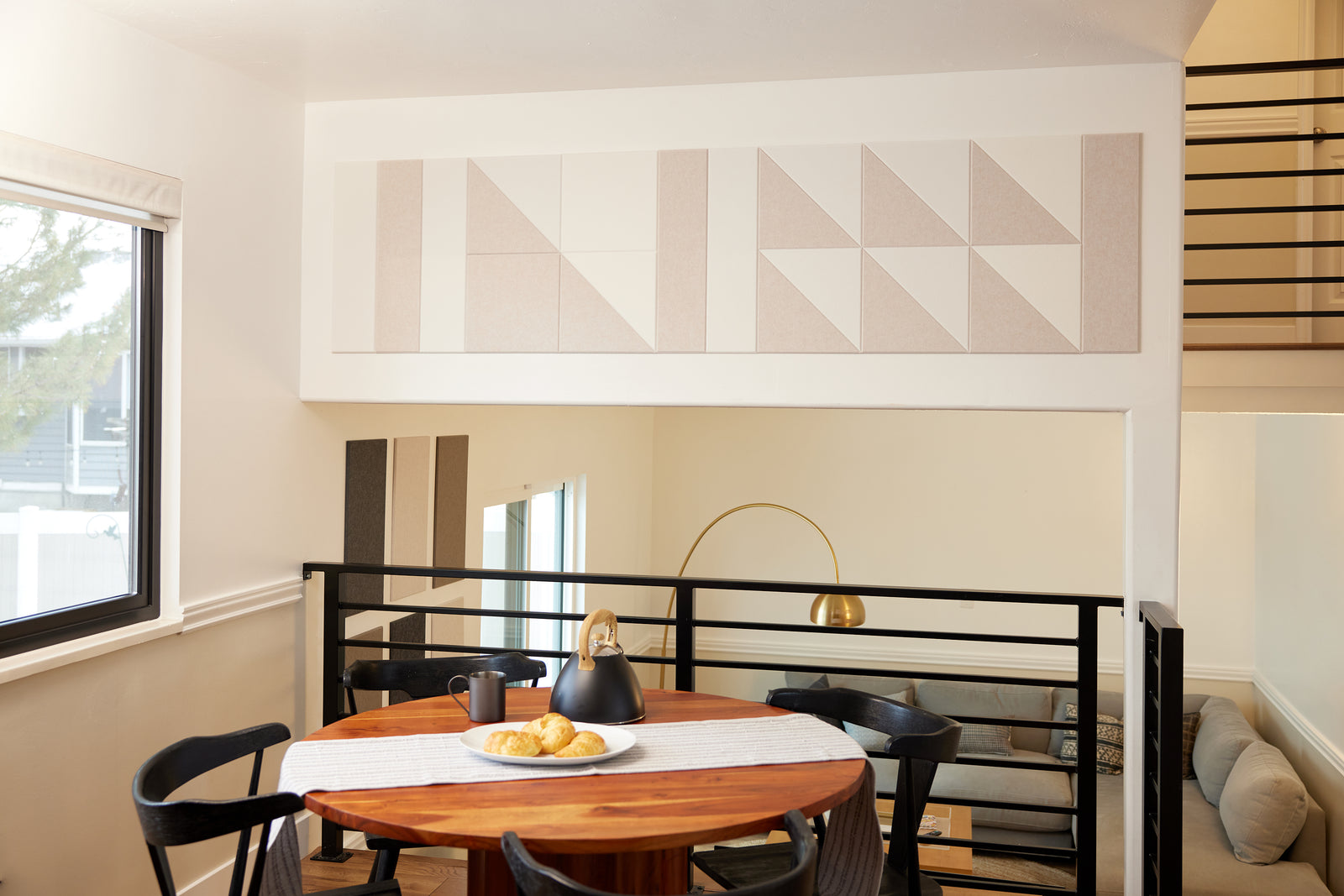 A Felt Right wall art design in cream shades on a wall above a kitchen table using triangles, squares and long rectangles.